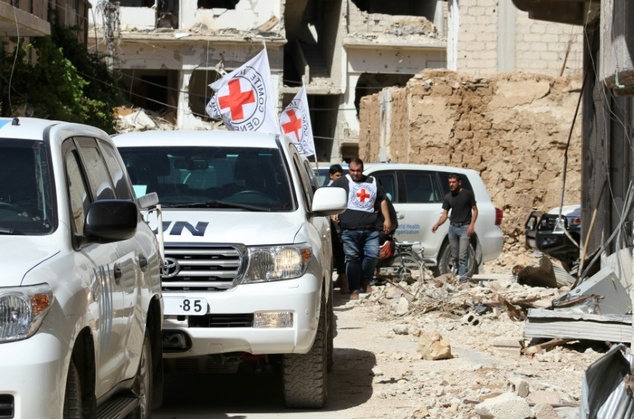 Vehicles of the International Committee of the Red Cross and the United Nations wait on a street after an aid convoy entered the rebel-held Syrian tow