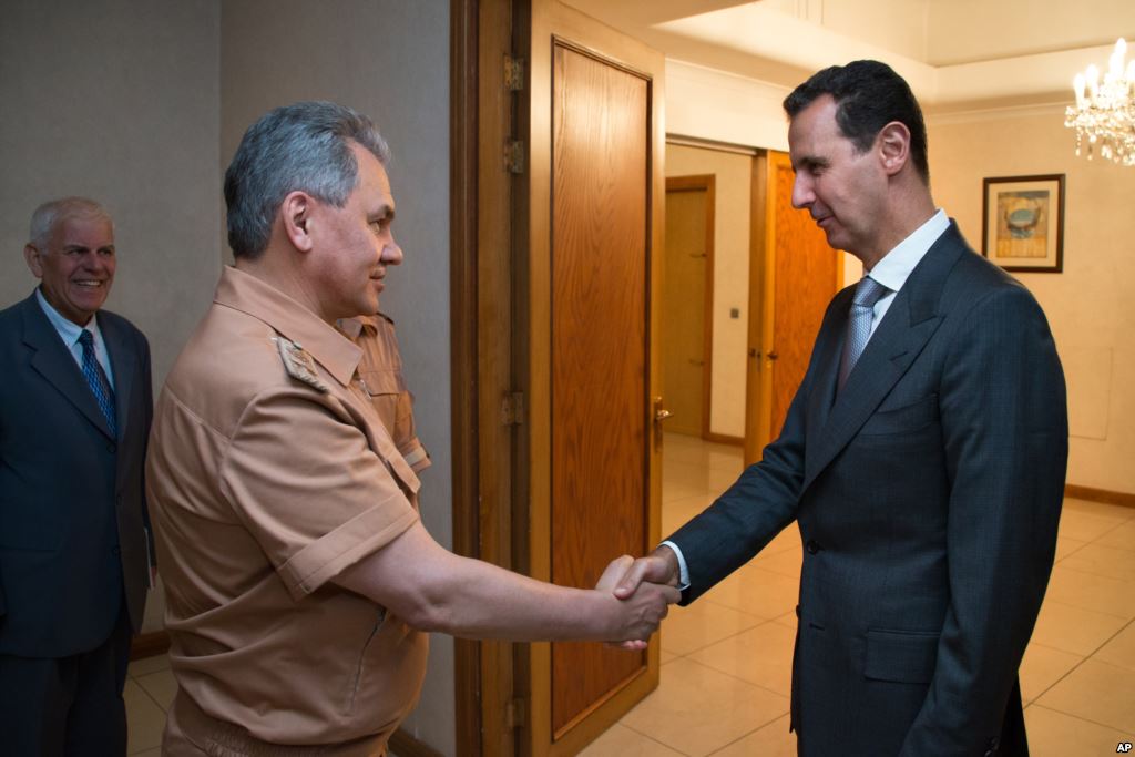 Syrian President Bashar al Assad shakes hands with Russian Defense Minister Sergei Shoigu in Damascus