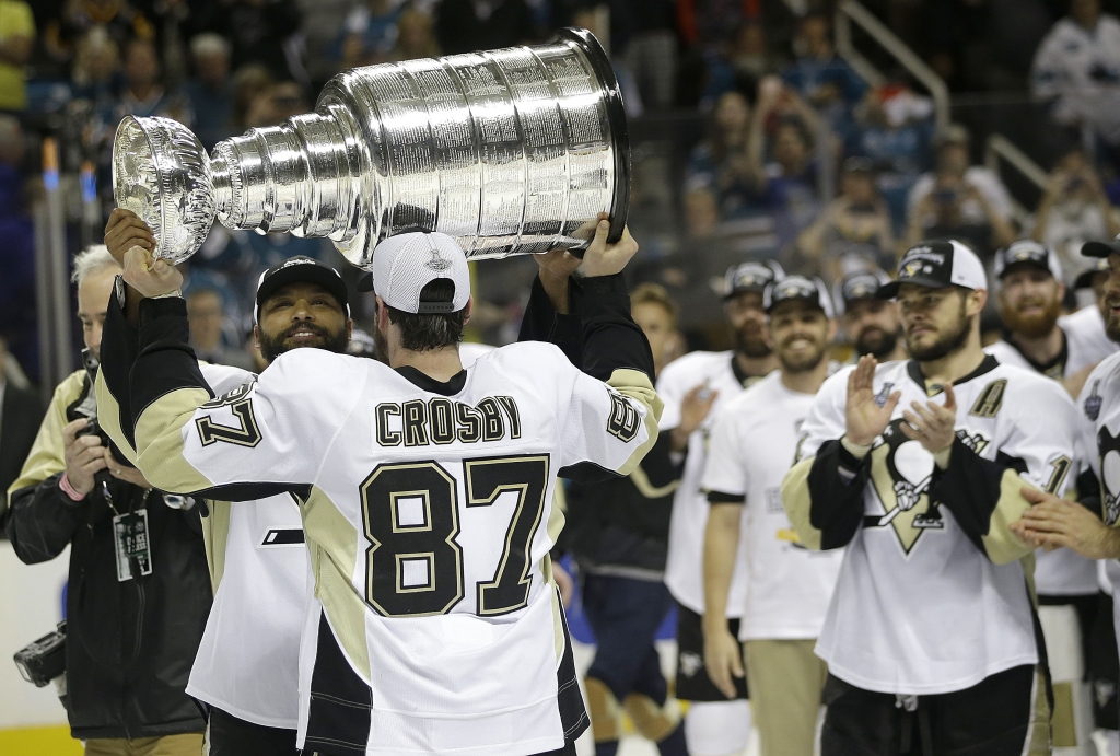 Pittsburgh Penguins center Sidney Crosby hands the Stanley Cup to defenseman Trevor Daley after Game 6 of the NHL hockey Stanley Cup Finals against the San Jose Sharks in San Jose Calif. Sunday