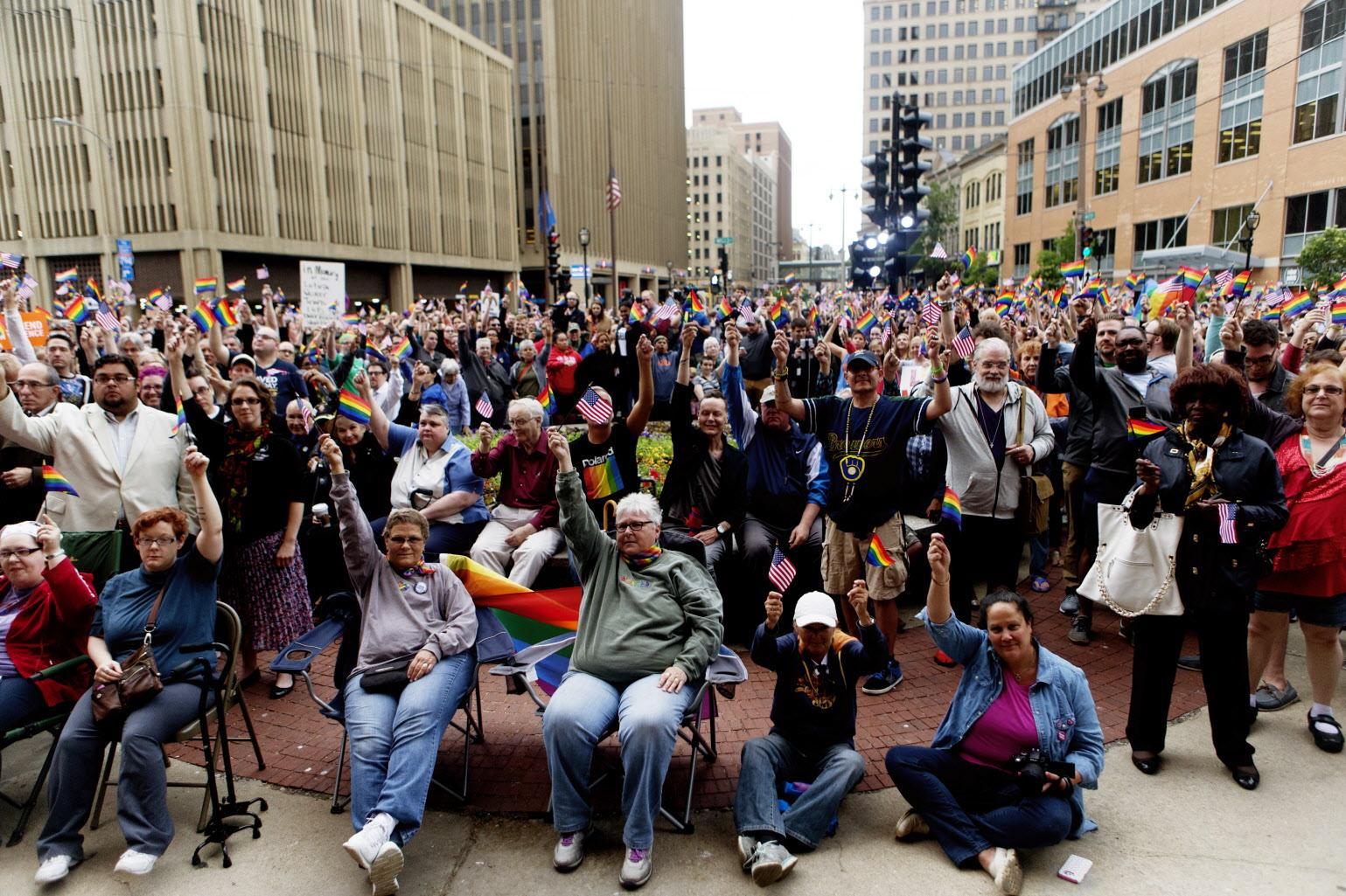 Attendees wave American and LGBTQ flags during a vigil held for victims of the Orlando Fla. mass shooting at Milwaukee City Hall Monday evening. CALVIN MATTHEIS