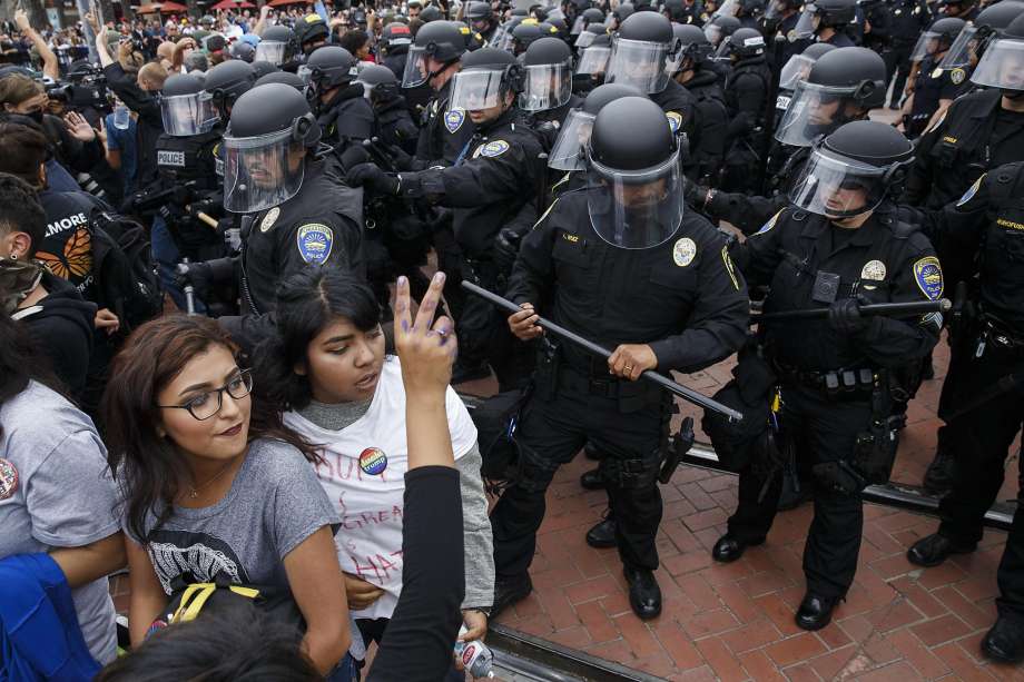 Police officers in riot gear stand guard as about 1,000 demonstrators protest Republican presidential candidate Donald Trump’s appearance at the San Diego Convention Center