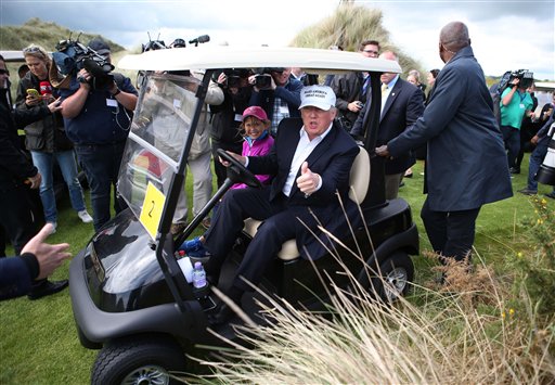 US presidential candidate Donald Trump chats with the watching media aboard a golf cart with granddaughter Kai after he arrived at the Trump International Golf Links at Balmedie near Aberdeen Scotland Saturday