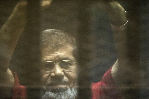 Egypt's ousted Islamist president Mohamed Morsi gestures from behind the defendant's bars during a previous court appearance in Cairo