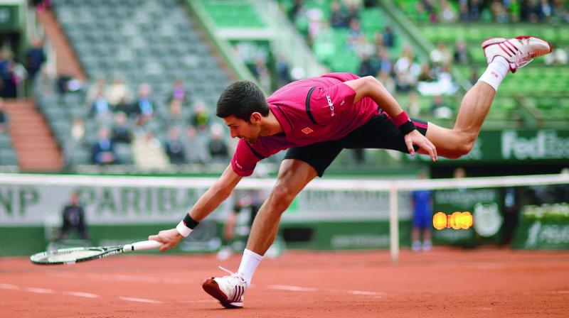 Novak Djokovic reaches for a return against Tomas Berdych during their French Open quarterfinal at Roland Garros in Paris on Thursday. Djokovic won 6-3 7-5 6-3