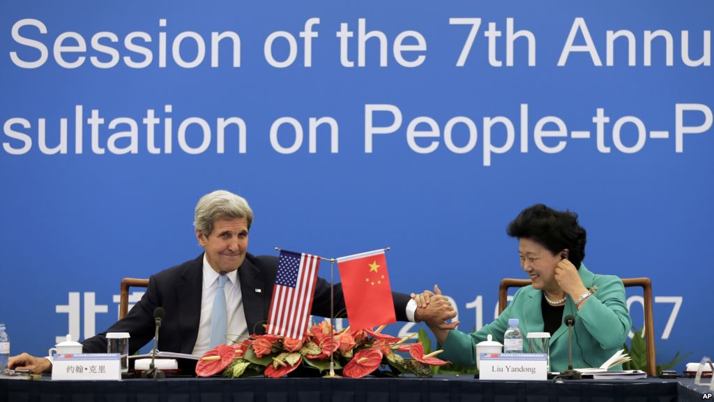 U.S. Secretary of State John Kerry left holds the hand of Chinese Vice Premier Liu Yandong after delivering a speech for the plenary session of the 7th annual U.S.-China High Level Consultation on People-to People Exchange at the National Museum in Beij