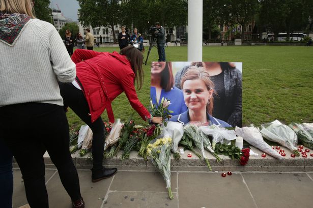 A woman lays some flowers at Parliament Square opposite the Palace of Westminster central London in tribute to Labour MP Jo Cox