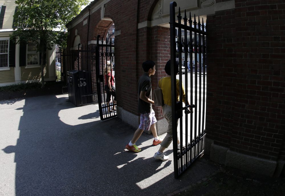 Pedestrians walk through a gate on Harvard University's campus