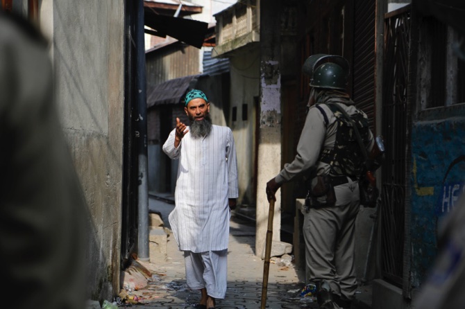 A Kashmiri man speaks with Indian soldiers for permission to cross a road during curfew in Srinaga