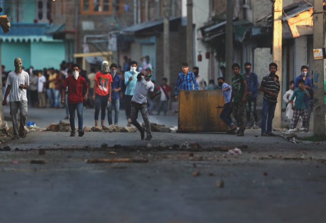 A Kashmiri protester throws a stone at Indian policemen during a protest in Srinagar