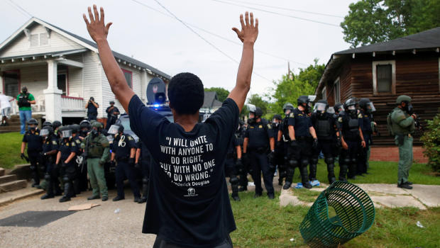 A demonstrator raises his hands in front of police in riot gear during protests in Baton Rouge Louisiana