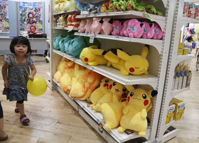 A girl walks past stuffed toys of Pokemon characters displayed on the shelves for sale during a Pokemon festival in Tokyo on July 18