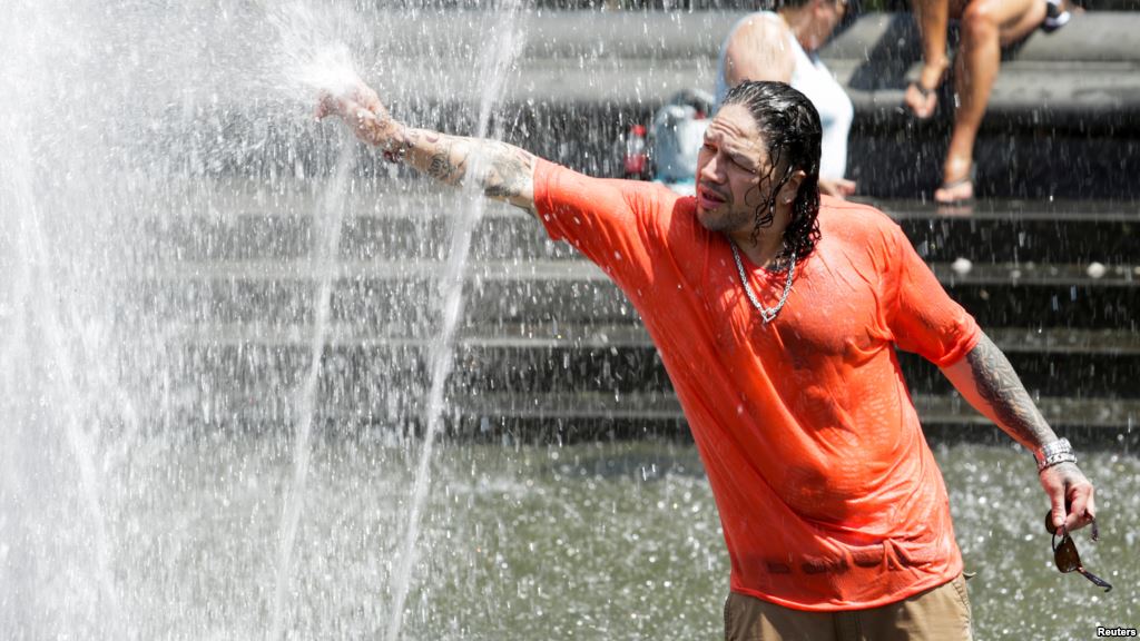 A man enjoys a cooling spray from a fountain during a heat wave in Manhattan New York