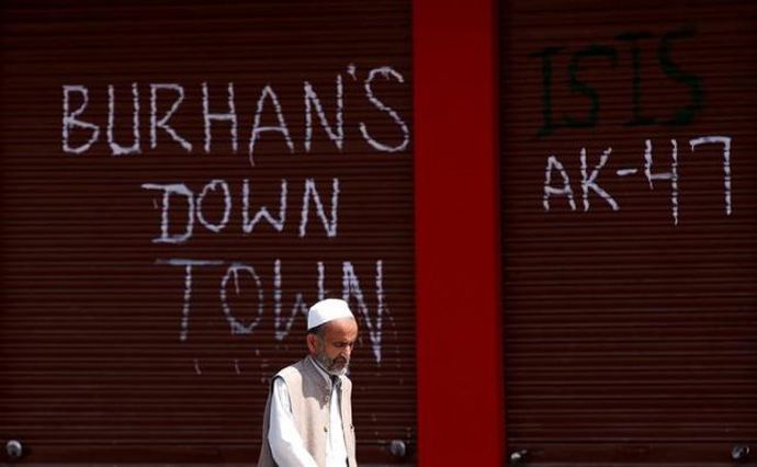 A man walks past closed shops painted with graffiti during a curfew in Srinagar