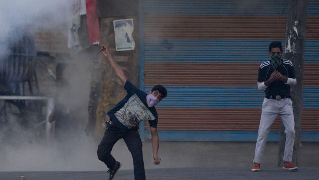 A masked Kashmiri protester throws a stone at policemen during a protest in Srinagar Kashmir