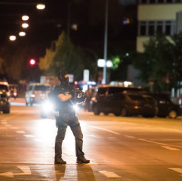 A masked policeman stands on the street in front of the Olympia mall where the massacre took place