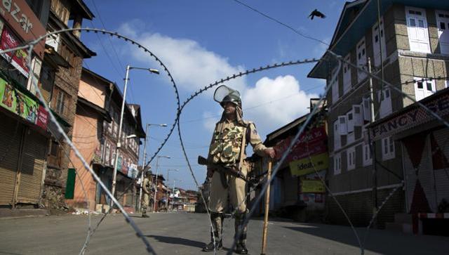 A paramilitary soldier stands guard near a temporary checkpoint during curfew in Srinagar