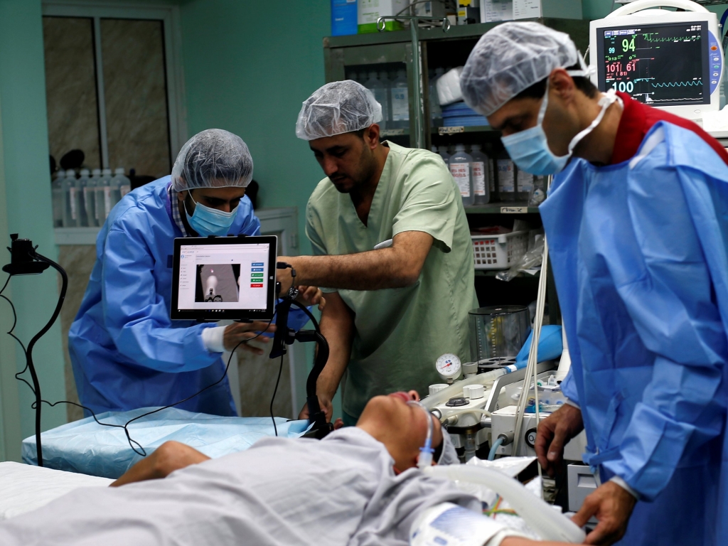 A patient lies on a bed as a technician left adjusts a screen before the start of surgery.   REUTERS  Suhaib Salem