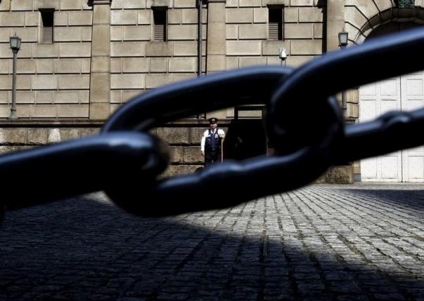 A security officer is seen through a chain link as he stands guard outside the Bank of Japan headquarters in Tokyo Japan