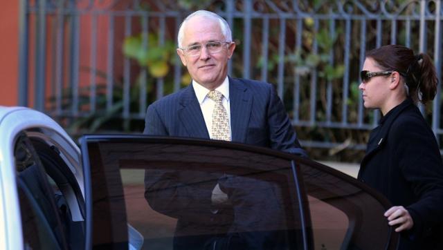 A security official assists Australian Prime Minister Malcolm Turnbull get into a car outside his home in Sydney