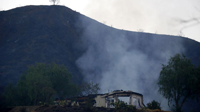 A smoldering home off the 26700 block of Iron Canyon Road is seen on the morning