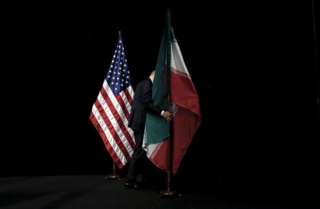 A staff member removes the Iranian flag from the stage during the Iran nuclear talks in Vienna Austria