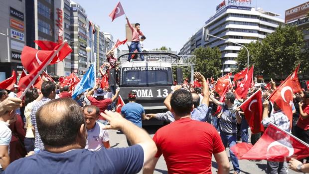 A supporter of Turkish President Tayyip Erdogan celebrates with flag on top of a police car in Ankara Turkey