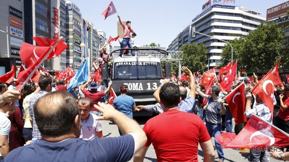 A supporter of Turkish President Tayyip Erdogan celebrates with flag on top of a police car in Ankara Turkey