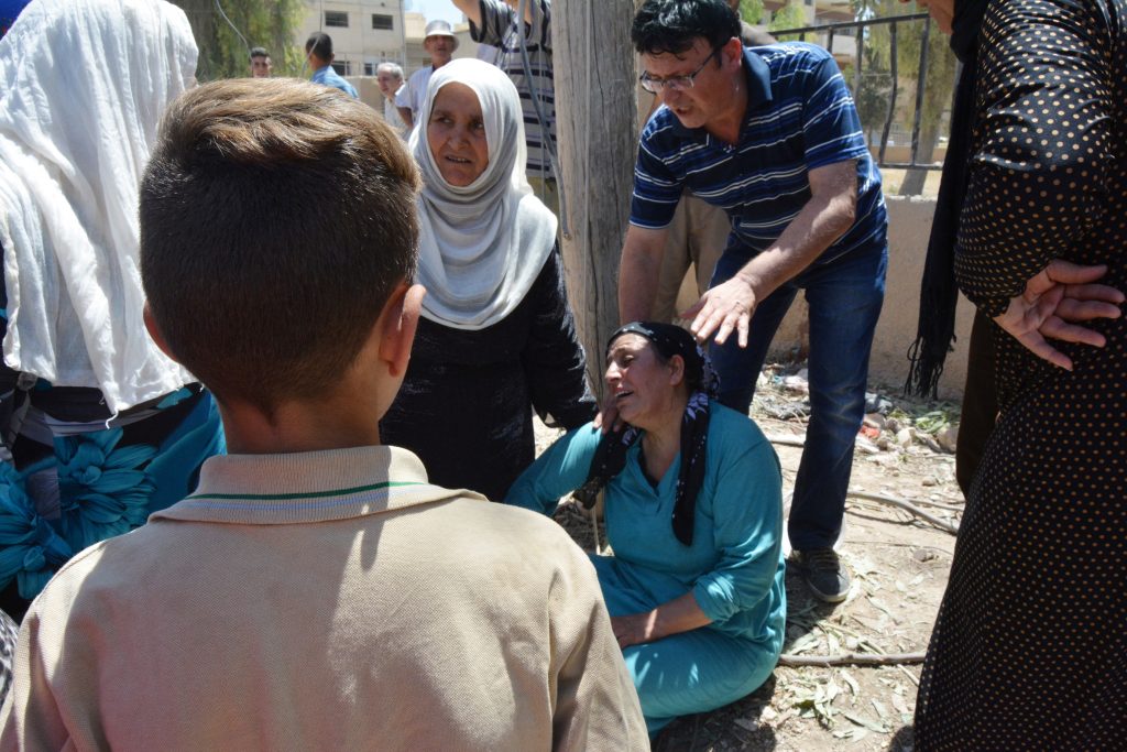 A woman mourns dead relatives at the damaged site in Qamishli