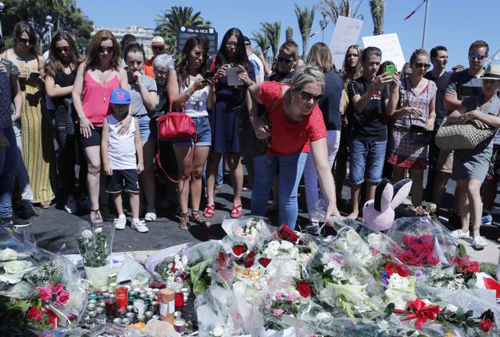 A woman puts flowers near the scene where a truck mowed through revelers in Nice southern France