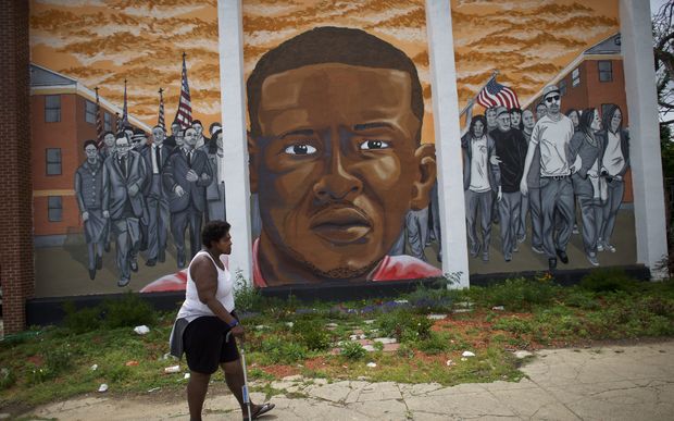 A woman walks past a mural of Freddie Gray in Baltimore