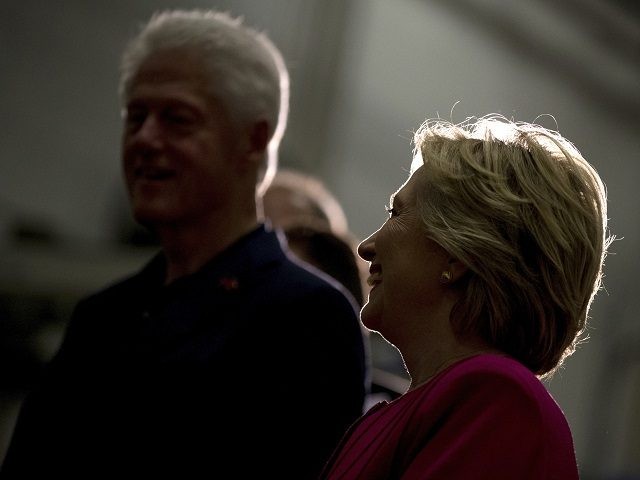 Former President Bill Clinton left and Democratic presidential candidate Hillary Clinton right are silhouetted by a light as they attend a factory tour of K'NEX a toy company in Hatfield Pa. Friday