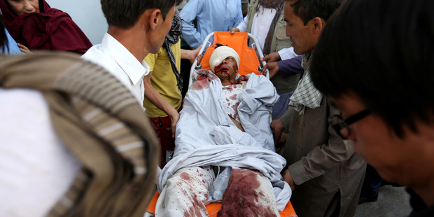 Afghans help a man who was injured in a deadly explosion that struck a protest march by ethnic Hazaras in Kabul