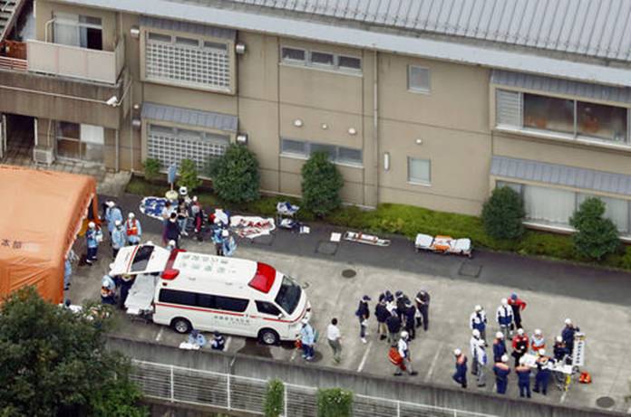 Ambulance crew and police officers are seen outside the facility