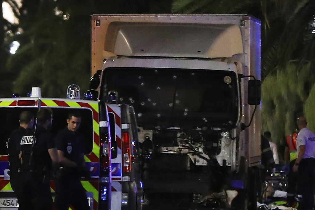 Police officers and rescued workers stand near a van that ploughed into a crowd leaving a fireworks display in the French Riviera town of Nice