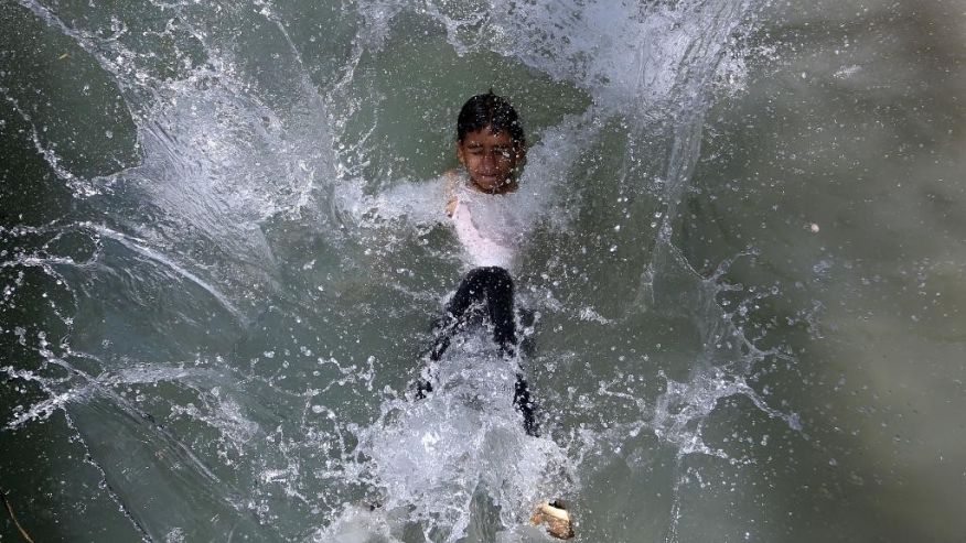 An Afghan teenager jumps into a canal on the outskirts of Kabul Afghanistan on Wednesday