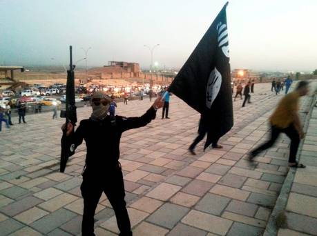 An Isil fighter waves a flag on a street in the city of Mosul Iraq