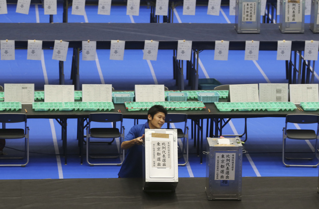 An election staff member carries a ballot box for voting at a ballot counting center in Tokyo Sunday