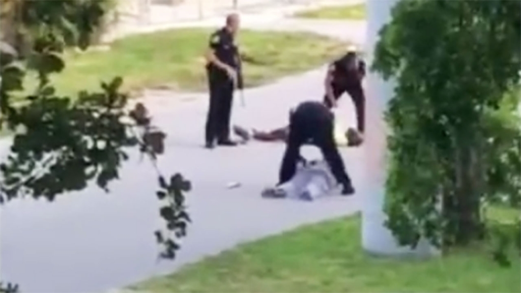 An officer shot the unarmed black man in the leg while he was lying on the road trying to calm his patient