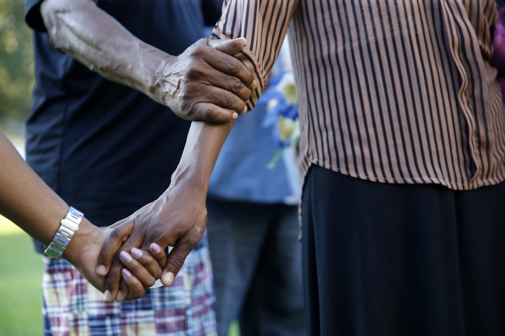 People hold hands in prayer at a candlelight vigil for Baton Rouge police officer Montrell Jackson outside Istrouma High School where he graduated in 2001 in Baton Rouge La. Tuesday