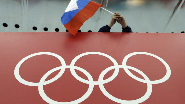 Russian skating fan holds the country's national flag over the Olympic rings before the start of the men's 10,000-meter speedskating race at Adler Arena Skating Center during the 2014 Winter Olympics