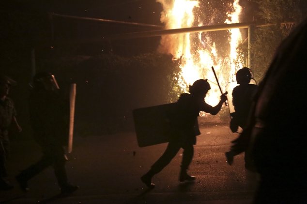 Riot police run to confront anti-government protesters supporters of the armed group who have been holed inside a police station clash with police in Yerev