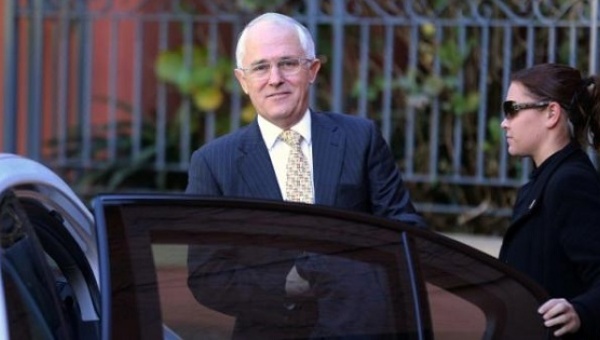 A security official assists Australian Prime Minister Malcolm Turnbull get into a car outside his home in Sydney Australia