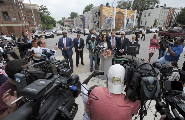 Baltimore State's Attorney Marilyn Mosby at podium holds a news conference near the site where Freddie Gray depicted in mural in background was arrested after her office dropped the remaining charges against three Baltimore police officers awaiting