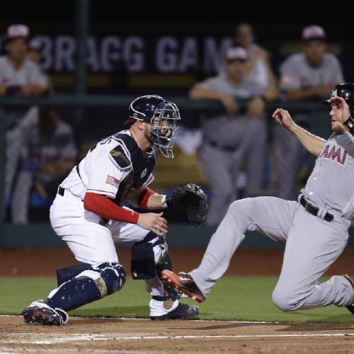 J.T. Realmuto slides safely past Atlanta Braves&#039 catcher Tyler Flowers to score a run during the fifth inning of a baseball game in Fort Bragg N.C. Sunday