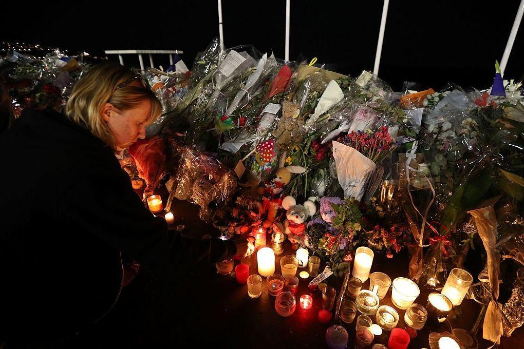 A woman lights a candle on Monday in Nice France by a makeshift memorial for the victims of the deadly Bastille Day attack