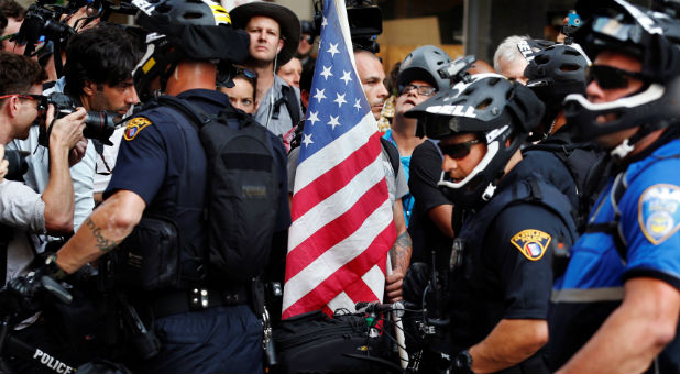 A protester with a U.S. flag confronts Cleveland Police police officers during a protest near the Republican National Convention in Cleveland Ohio