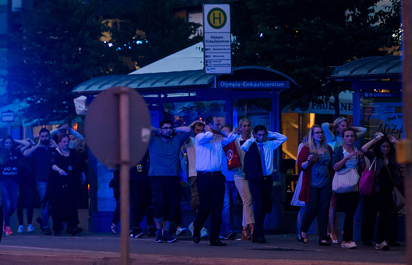 MUNICH GERMANY- JULY 22 Police officers escort people with their hands raised from inside the shopping center as they respond to a shooting at the Olympia Einkaufzentrum