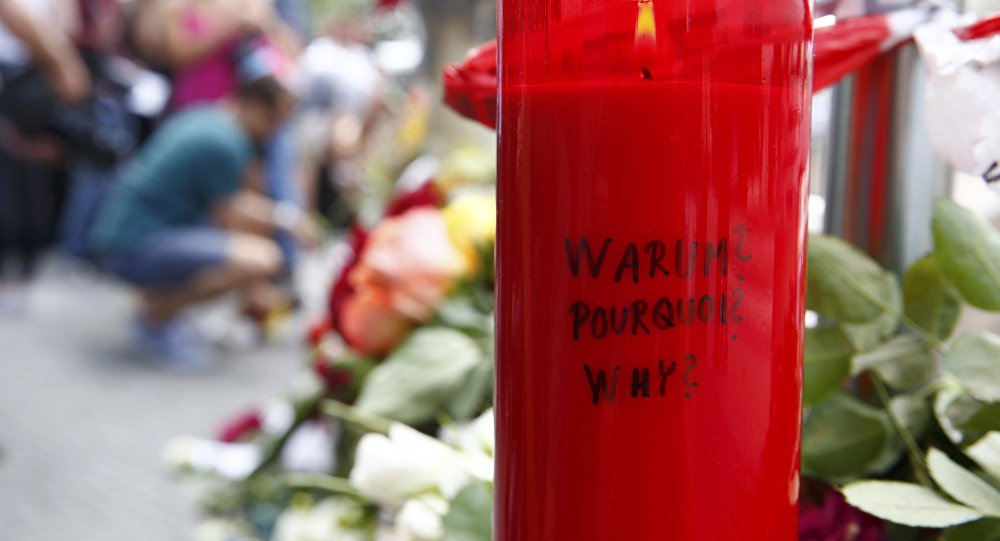 A candle with the words'Why? written upon it is placed next to flowers near the Olympia shopping mall where yesterday's shooting rampage started in Munich Germany