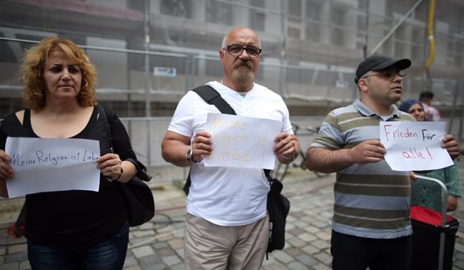 GERMANY OUT- Refugees from Syria and Iraq stand near the site of the attack and hold up signs reading 'Peace for all&#39, right and 'My religion is love&#39 left and center in Ansbach Germany Tuesday