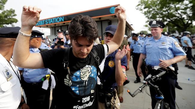 A demonstrator is taken into custody by police after climbing over a barricade near the AT&T Station Monday